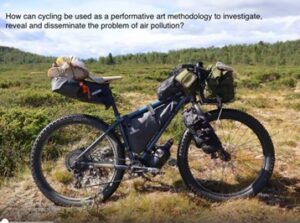 An image of Clare Nattress' bike in a rural terrain, it reads 'how can cycling be used as a performative art methodology to investigate and disseminate the problem of air pollution?'