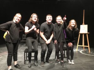Five students, wearing all black in a stuio space