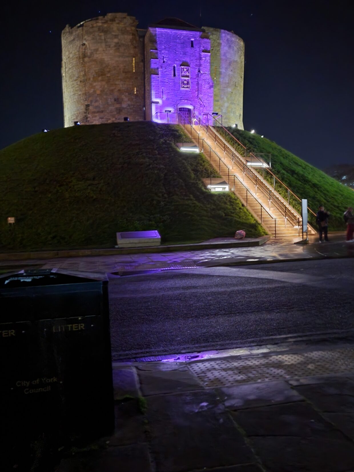 Cliffords Tower on Bonfire Night. The sky is dark and a purple light lights up Clifford's Tower.