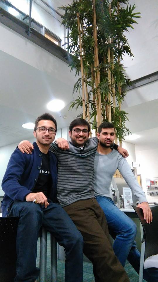Syed Kamal, Usman and Ab sit in the library. They wear dark trousers and dark coloured jumpers. The three students have short dark brown hair.