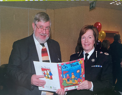 Image of John holding a book titled "on track"