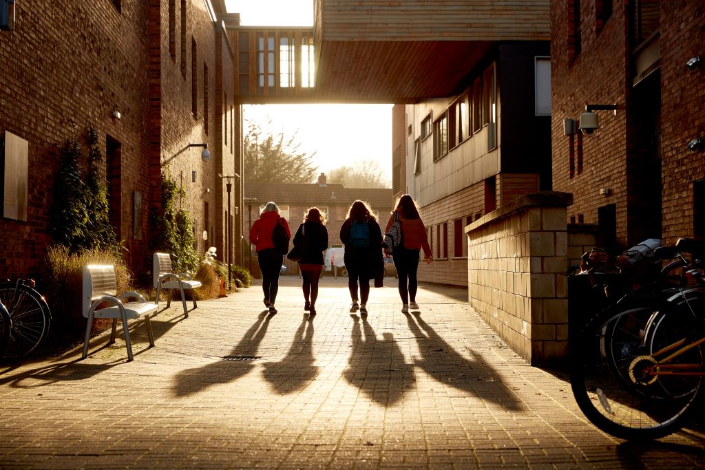 Four students walking away in between buildings on campus.