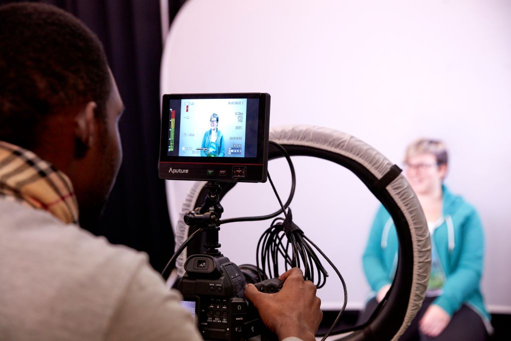A media student looking at the image on camera while filming.