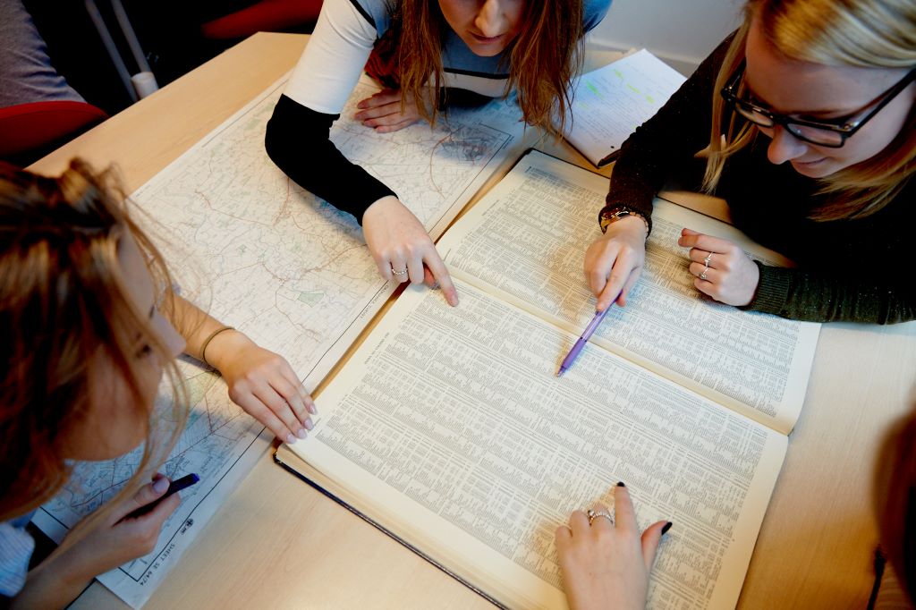 Geography students at a table, reading the index of a map.