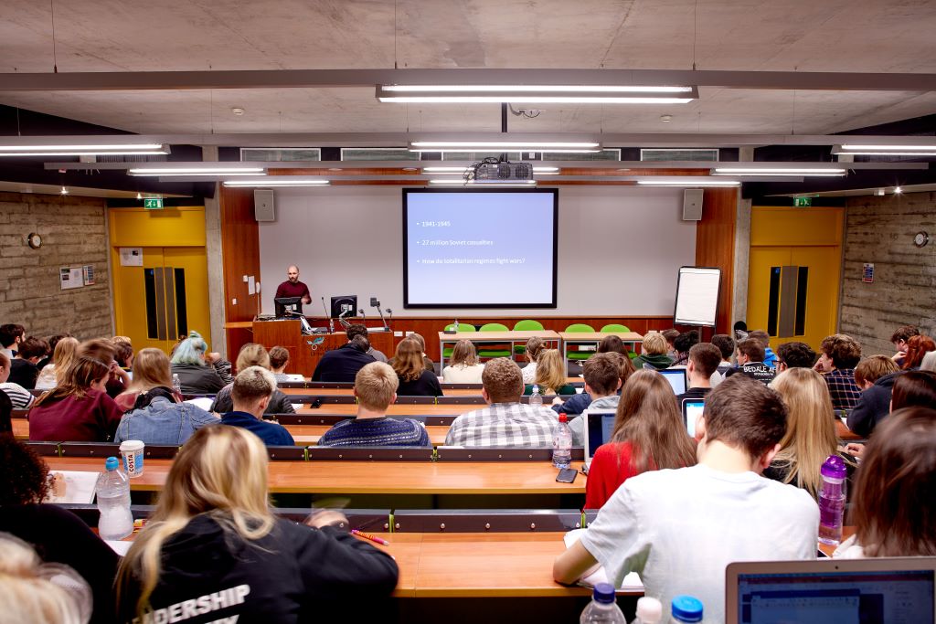Students facing a whiteboard during a lecture.