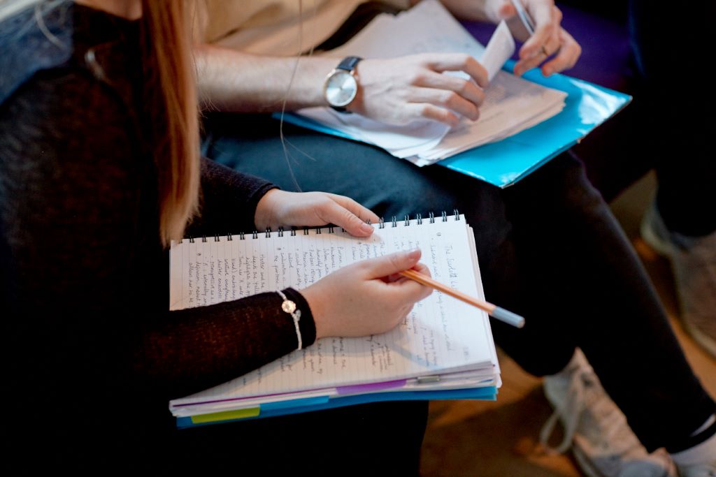 A student with a notepad on their lap, handwriting notes.