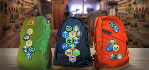 Photograph of a green, navy and red backpack with badges sewn onto them.